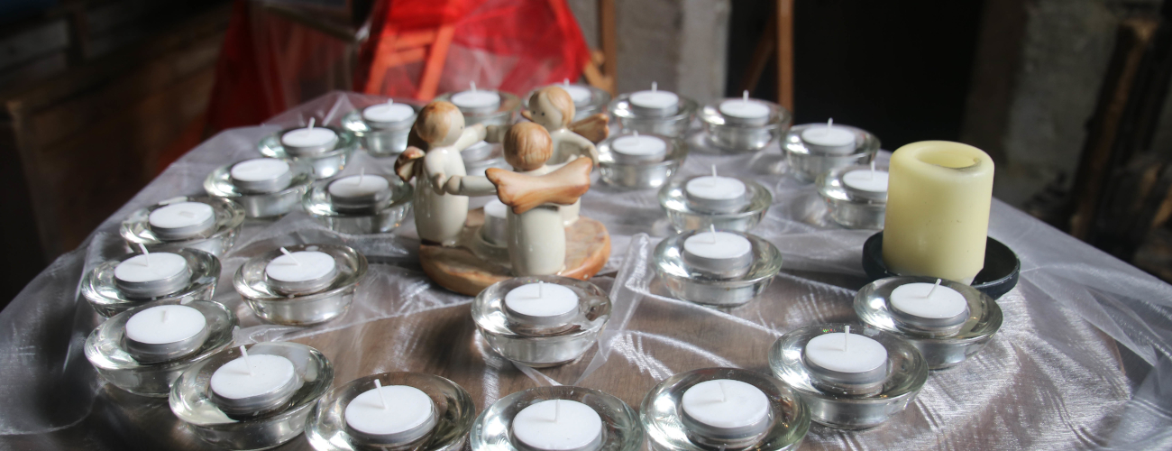 concentric circles of small candles with a central statue of three angels holding hands